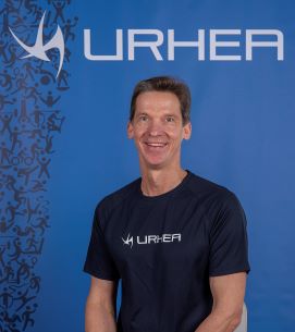 Juha Dahlström katsoo kameraan Urhea-logon edessä