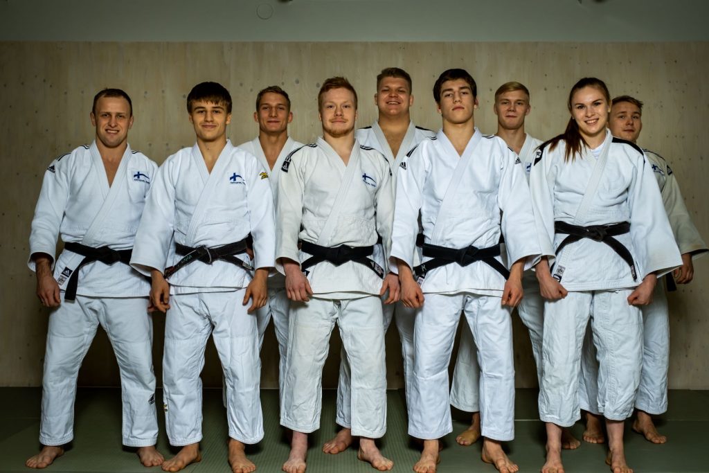 9 judokaa seisoo ryhmänä kasvot kameraan päin ja hymyilee