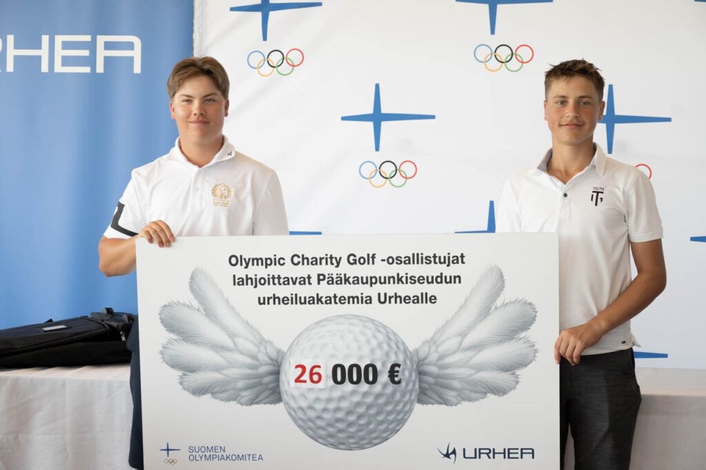 Kaksi nuorta miestä pitelevät Olympic Charity Golfin shekkiä, jossa lukee
"Olympic Charity Golf -osallistujat lahjoittavat Pääkaupunkiseudun urheiluakatemia Urhealle 26 000€"