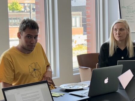 Aku Nikander ja Anna Kirjavainen istuvat pöydän ääressä, tietokoneet ovat heillä edessä pöydällä. Nikander puhuu.