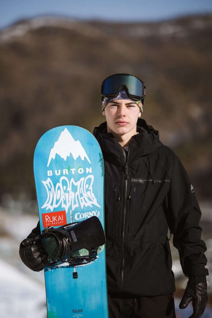 Ville Jukola seisoo lumella lumilaudan kanssa, lumilauta on pystyssä Jukolan vieressä